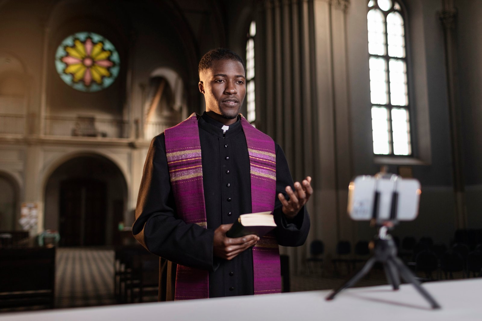 young-male-priest-streaming-sermon-from-church-with-smartphone